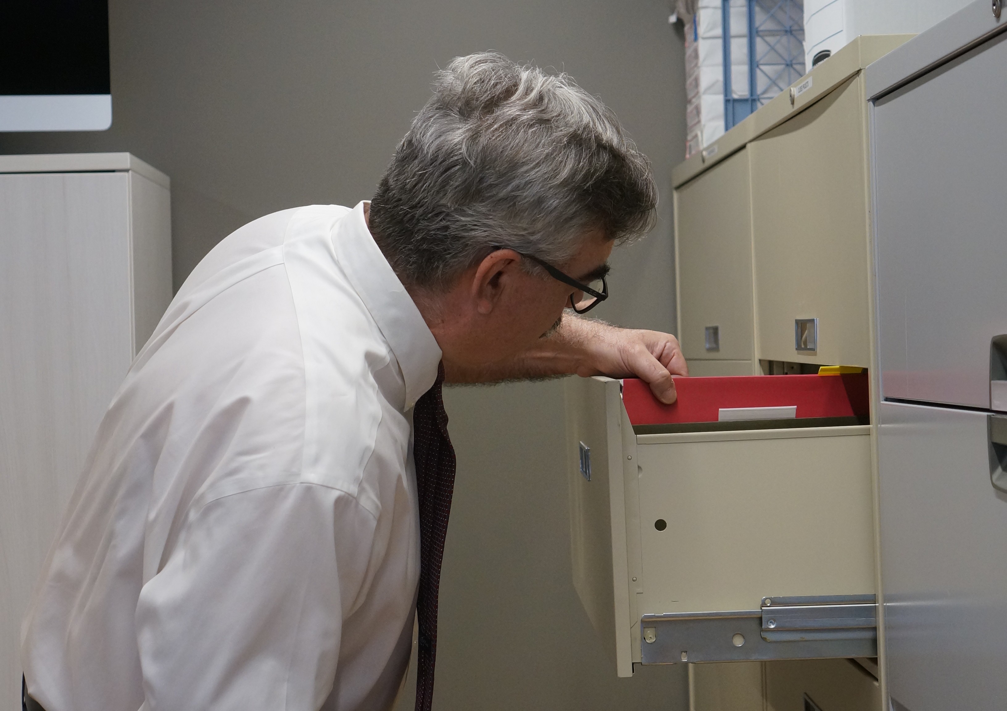 Al Beuscher, founder, looking at a filing cabinet.
